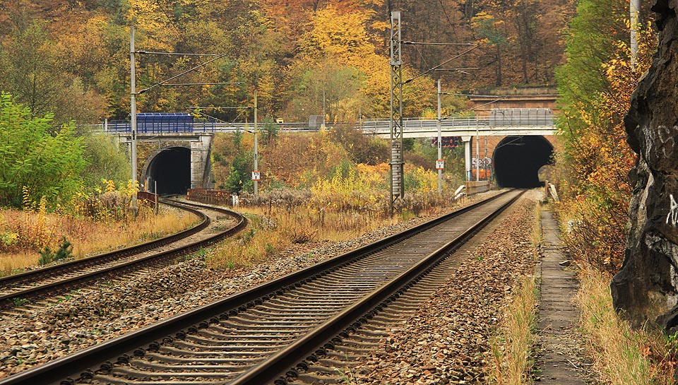 Pohled ze severu od místa oddělení obou kolejí železniční trati č. 260 do nového a starého Novohradského tunelu. Před tunely protéká řeka Svitava a za ní na mostě vede silnice II/379 mezi Blanskem a Lipůvkou.