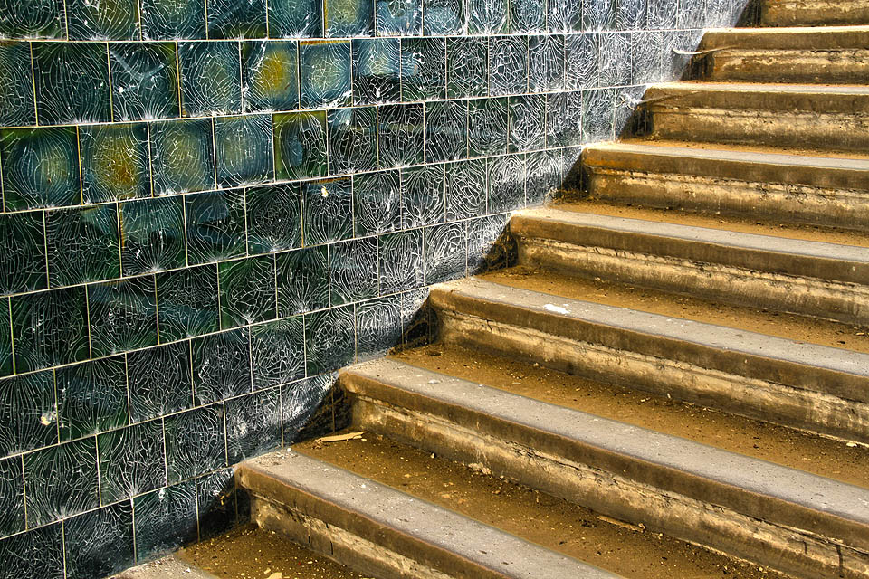 Zpátky na schodiště a po kamenných stupních o poschodí výše. Ale opatrně, zábradlí už také někdo spotřeboval.