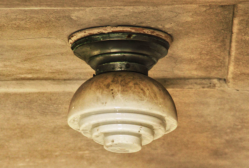 Schodiště osvětlují různé, avšak podobné lampy ve stylu art deco. Hranaté, kulaté, vždy se schodečky připomínajícími Fressnelovu čočku.