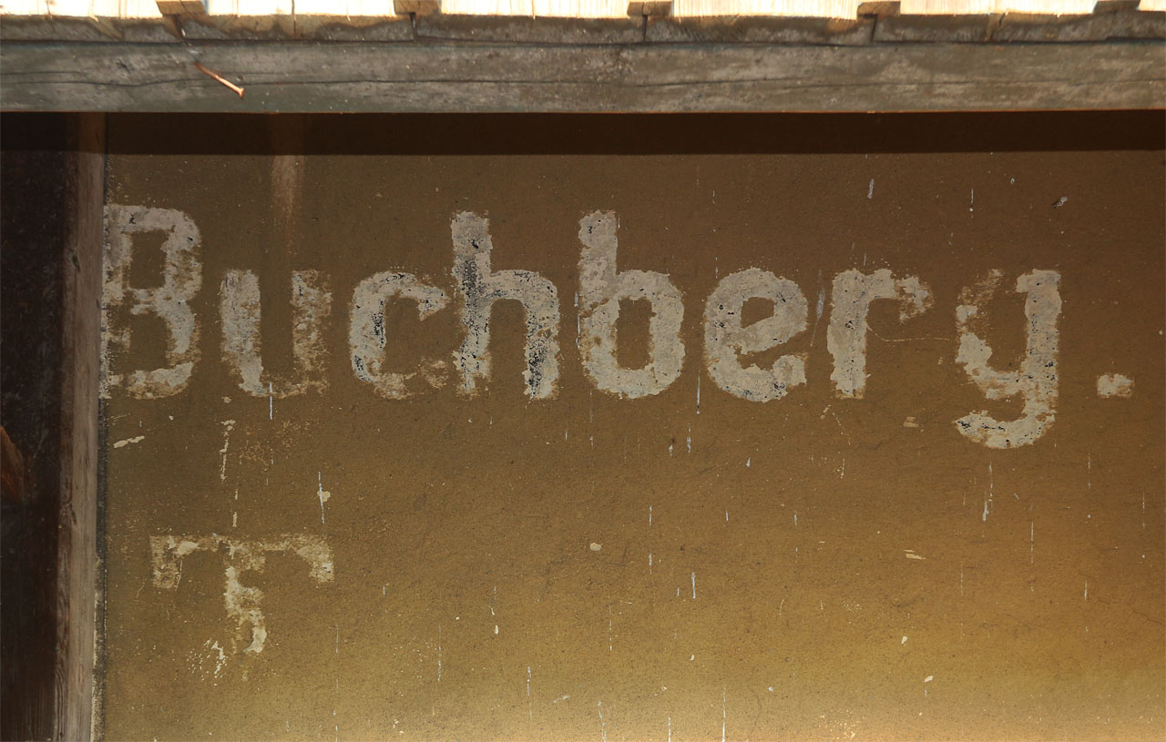 Dokladů o existenci zastávky v létech 1892–1945 není mnoho. Jedním z posledních je z omítky seškrábaný nápis Buchberg, ukrytý před vlivem povětrnosti pod přístavbou dřevěné verandy. Plechové cedule dávno odnesl čas, vyškrabání černých písmen však vytvořilo sekunární bílý vzor a dřevěná veranda ochránila místo před novým nátěrem.