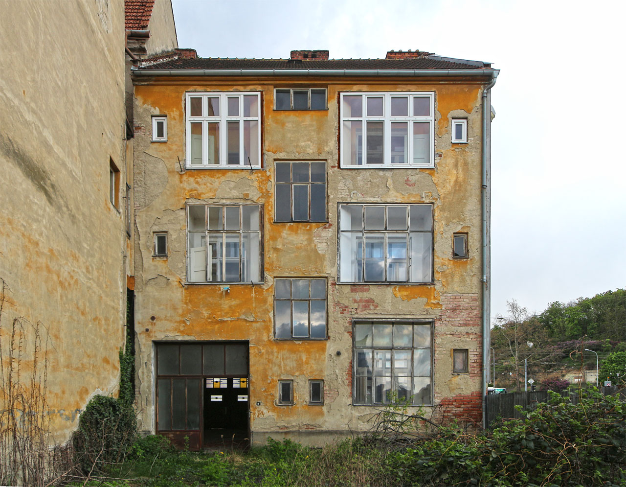 Denní pohled ze dvora na jedinečná prosklená okna. Jejich výhodou bylo náramné prosvětlení koupelen, nevýhodou ovšem poněkud omezené soukromí v nich.
