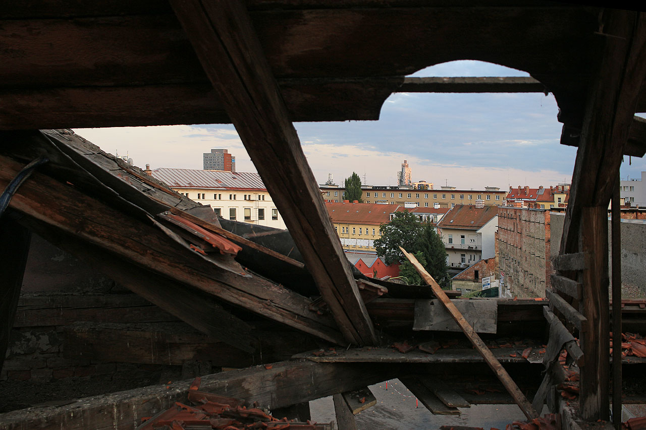 Výhled na Staré brno skrze rozpáraný vikýř. Poslední pavlačové domy se střídavým úspěchem odolávají naneštěstí obvykle nenápaditým moderním stavbám. Dožijí se alespoň některé i dalšího století?