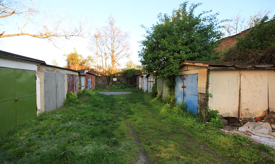 Úplně vzadu, tam kde již dvorek kradmě pokukuje po kolejiši hlavního nádraží, stojí hrstka starých garáží. Tak nějak si představujeme místo za Šmejkalovou ohradou.