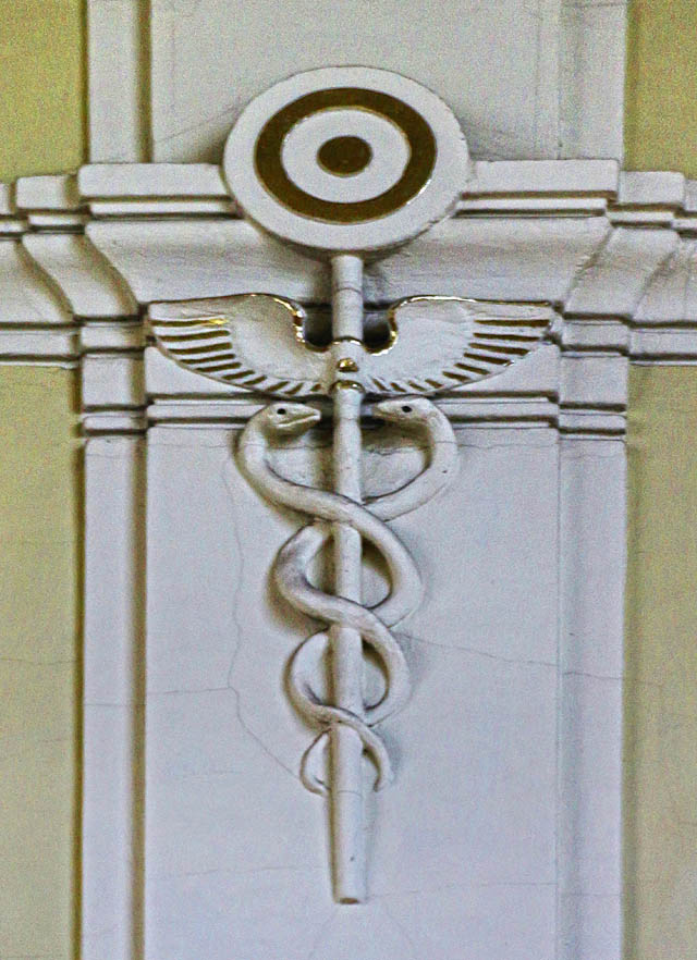 Mírně záhadná je štuková výzdoba v hale. Třeba okřídlenou výpravku ovinutou dvojicí hadů bychom čekali spíš v postmoderní budově z 21. století. Na vysvětlení tohoto secesního skvostu zatím čekáme.