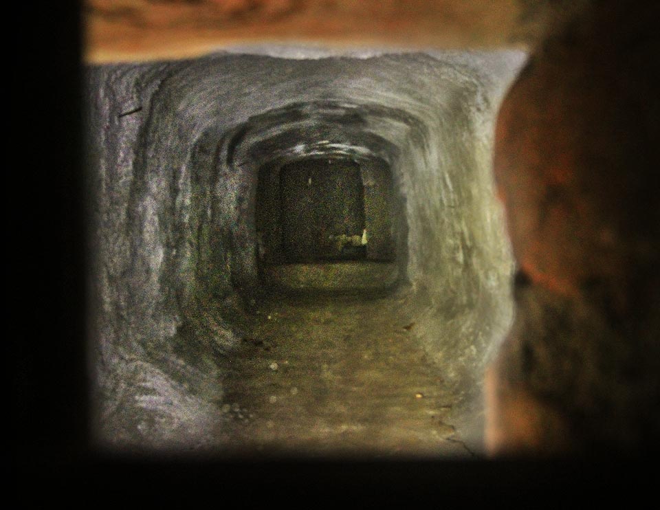 Miniaturním okénkem lze nahlédnout za stěnu pod poslední (v roce 2015) neobydlený a pustý dům na Pekařské ulici.