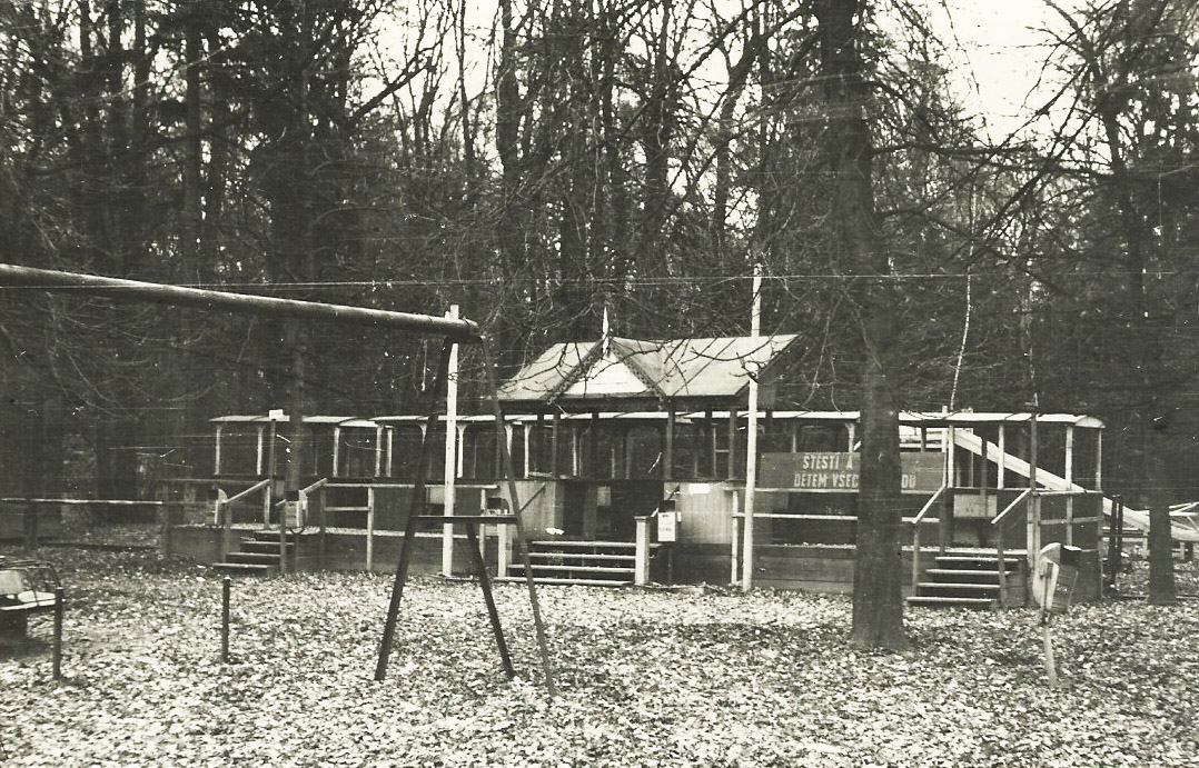 Hlavní stanice přerovské pionýrské železnice se soupravou vozů bez lokomotivy (v pozadí skluzavka na dětském hřišti). Štěstí a mír (a vlaky) dětem všech národů! Datum snímku je pouze přibližné, autorem je Vladimír Mokošín.