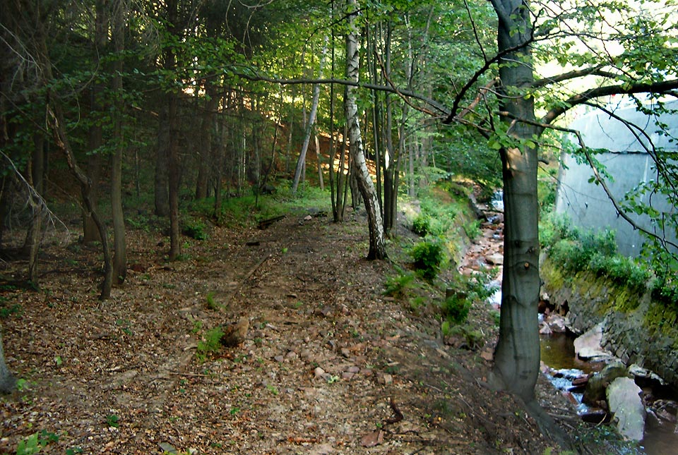 Zhruba tady stávala kdysi točna k obracení parních lokomotiv projíždějícíh úvratí. Dnes osamělé místo chřadne v hluku a špíně pod opěrnou zdí státní silnice, na kterou se v průběhu let náklady přestěhovaly z dráhy.