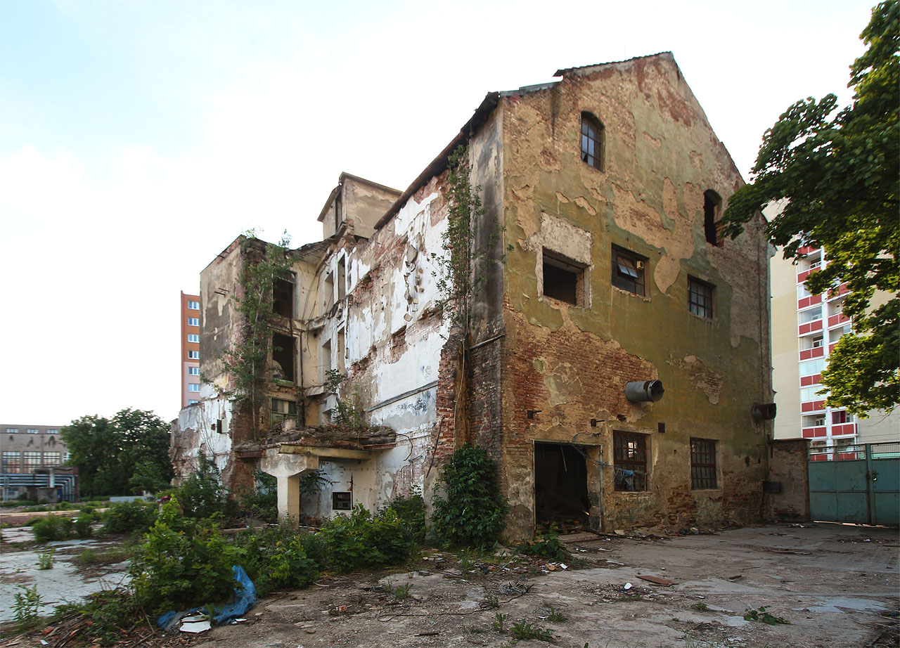 Pohled na severní štít svádí k myšlence, že byl dům vystavěn rovnou jako továrna. Nicméně nepravidelně umístěná okna by mohla svědčit i o pozdější adaptaci původně bytového domu.