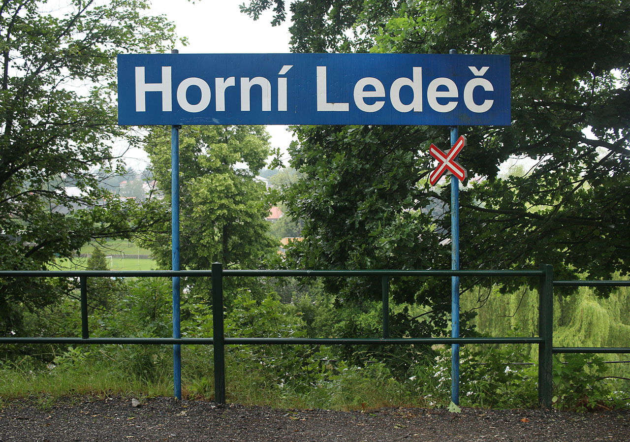 Stísněnost prostoru na zastávce vedla k unikátnímu spojení cedule s názvem zastávky a dopravní značky A32a Výstražný kříž pro železniční přejezd jednokolejný.