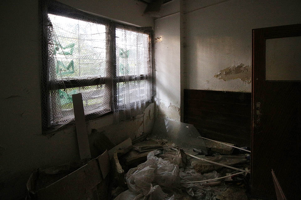 Některá okna tu ještě způsobně kryjí záclonky. Ve všech místnostech je ale ohromné množství nepořádku, tvořeného zmarnělými dokumenty a neprodejným zbožím.
