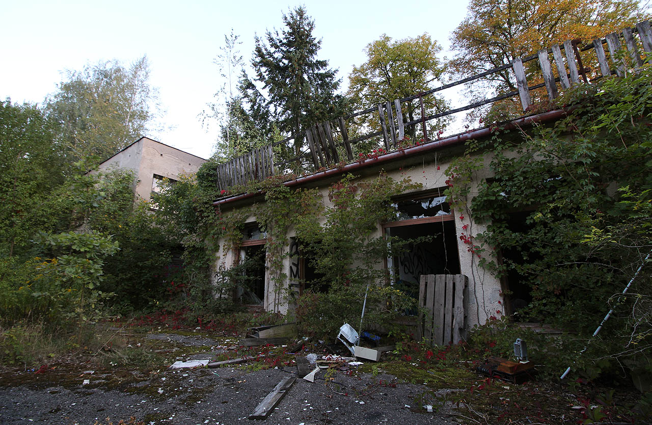 Přístavby různého stáří a žalostného stavu pokračují i ve dvoře budovy až postupně splývají s divokým houštím a nakonec lesem.