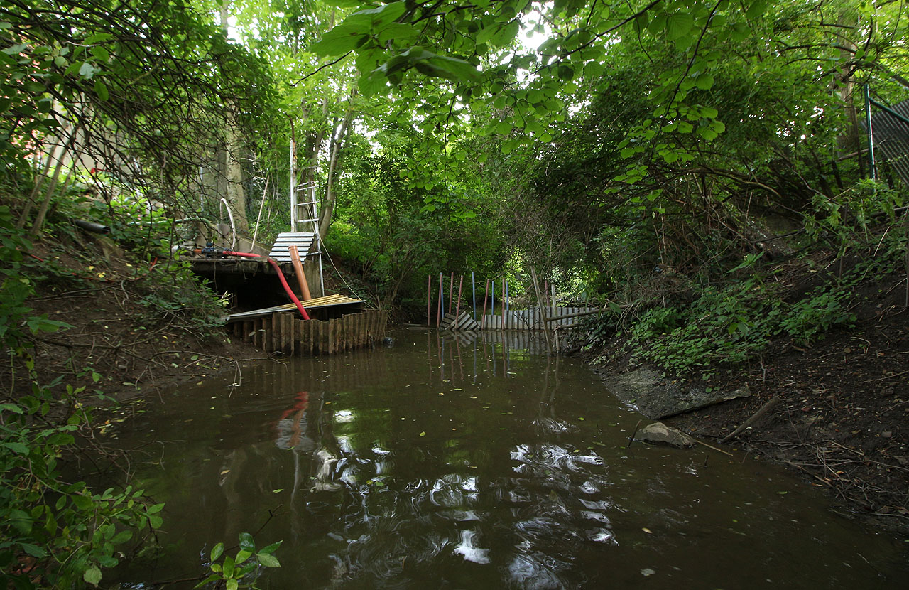 Dalším vodním dílem na náhonu je bariéra sloužící k vzedmutí hladiny pro potřeby čerpadla na zavlažování kurtů. Samozvaní stavitelé ji tu vybudovali zaražením kovovýh trubek do dna náhonu a o ně zapřeným vlnitým plechem.