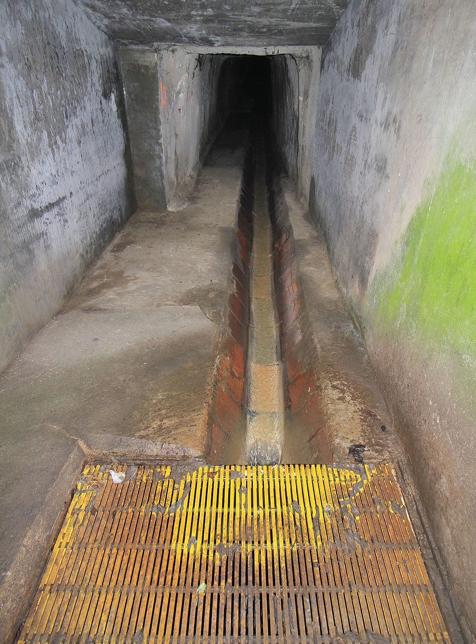 Žlutý poklop, česle, mříž, či jak lze nazvat laminátovou rohož kryjící spadiště shora, brání člověku v pádu do nebezpečné hlubiny. Dveře jsou dle očekávání po většinu doby zamknuté.