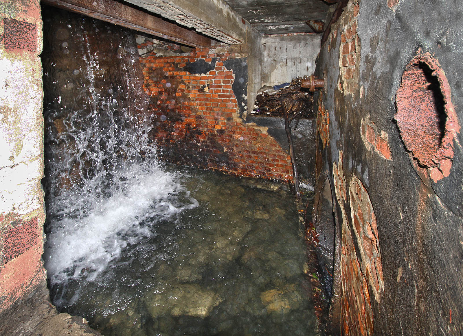 Jeden z mnoha vodních stupňů v temném podzemí budov. Část potoka pokračuje do hloubky pod dalším patrem, jiná část mizela v ocelových trubkách, dnes již většinou odřezaných.