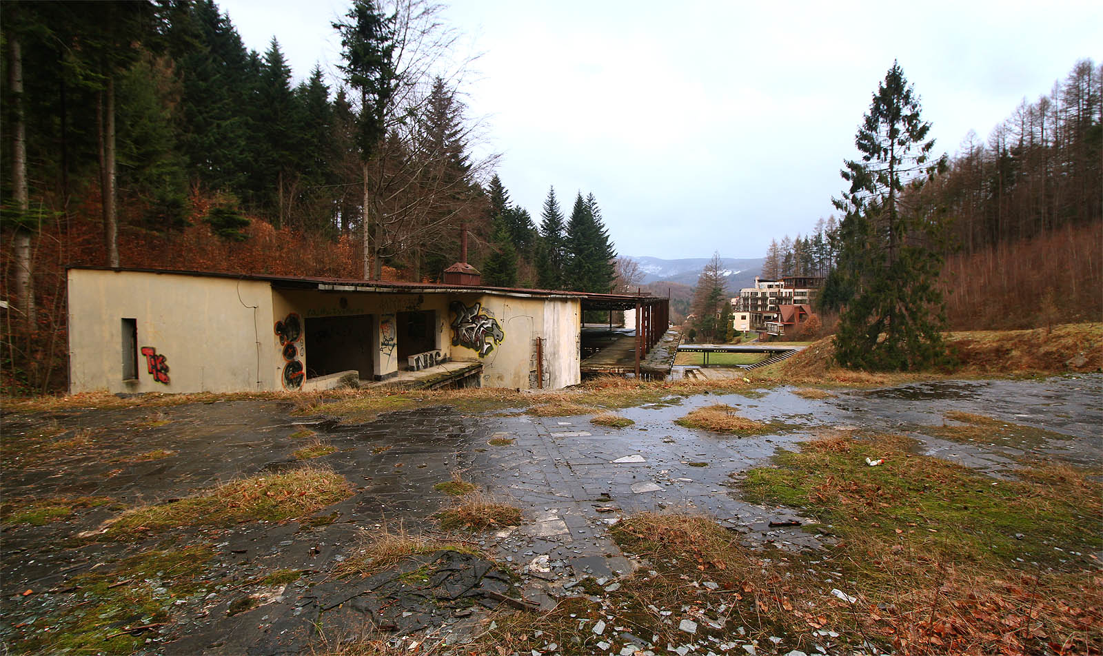 Pohled z terasy jedné z ústředních budov. Potok protéká o několik pater níže pod našima nohama, taneční parkety a okrasné lampy už dávno zmizely v propadlišti dějin.