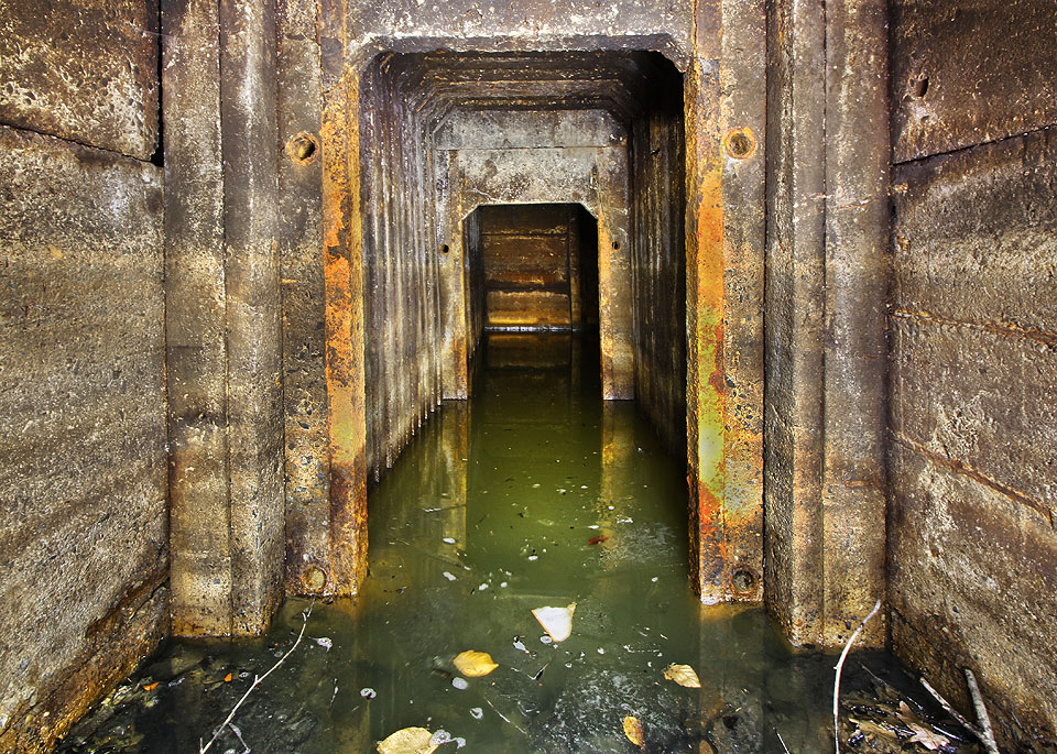 Záhy ale přichází zklamání. Neobvyklý kryt složený z úzkých betonových segmentů je zpola zatopen vodou a bahnem z tlejícího listí.