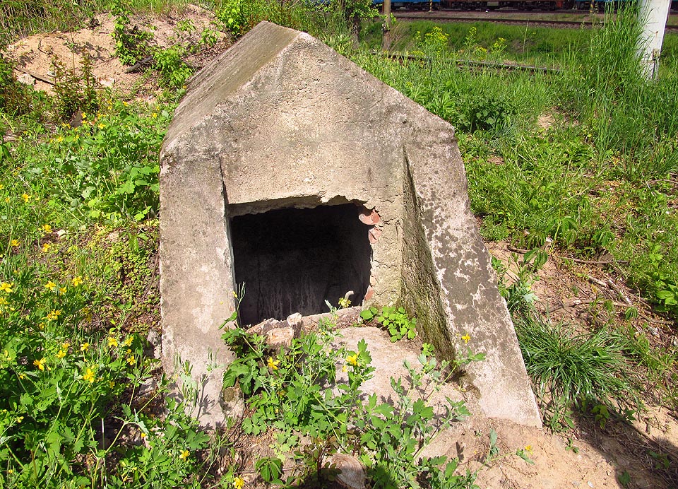 Hlavní a jediný vstup do krytu je nenápadný a vypadá jako malý betonový model nějaké jiné stavby.