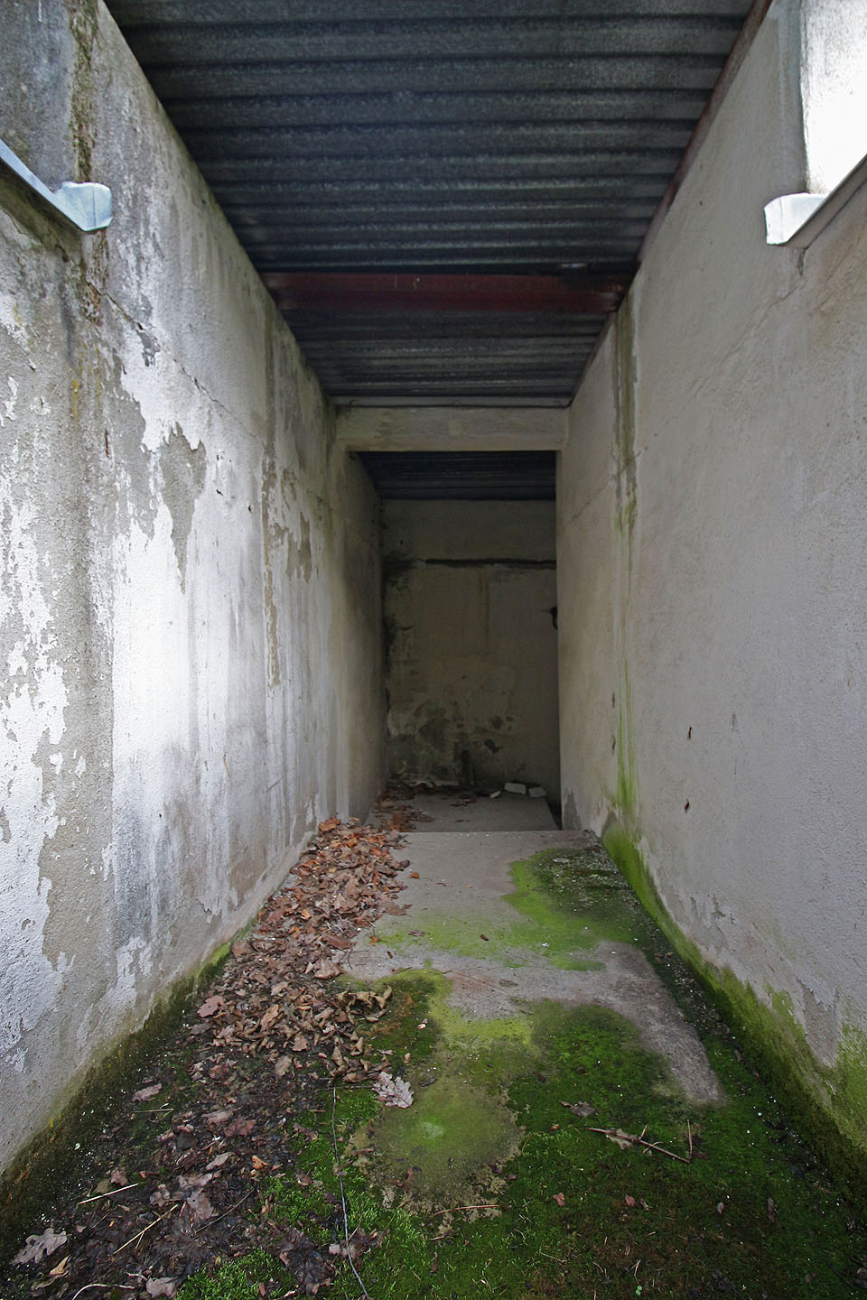 Vstup do krytu z východní strany. Schodiště není shora uzavíratelné, proti povětrnosti je chráněno jen chatrnou plechovou stříškou a nesymetrickou dvojicí zdí. Vstup do krytu z východní strany. Schodiště není shora uzavíratelné, proti povětrnosti je chráněno jen chatrnou plechovou stříškou a nesymetrickou dvojicí zdí.