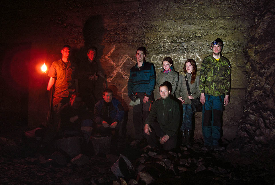 Společná fotografie pátracího týmu u bětonové stěny oddělující chodbu se zasypaným zadním východem od zbytku stěn. Výzdoba je autentická.