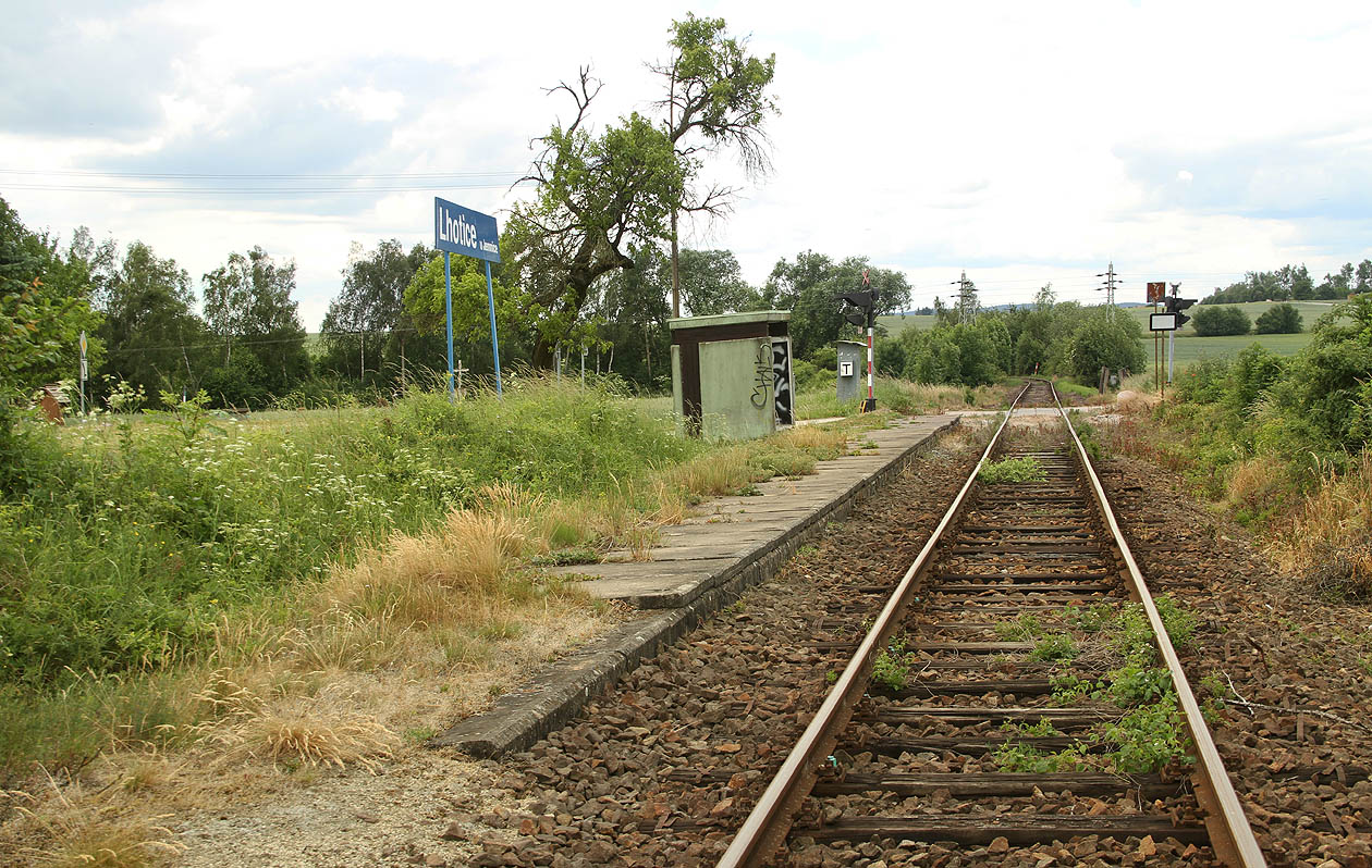 Pohled od severovýchodu na zřídka využívanou zastávku a přejezd přes silnici Lhotice–Jemnice.