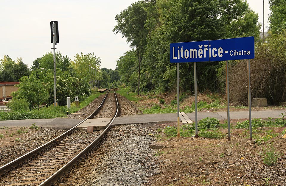 Pohled na zastávku od severu, přibližně z místa, kde křížila dráhu úzkokolejka vedoucí k podzemní továrně Richard. Na ceduli je název uveden v souladu s pravidly pro názvy zastávek a stanic, ale v rozporu s oficiálními údaji.