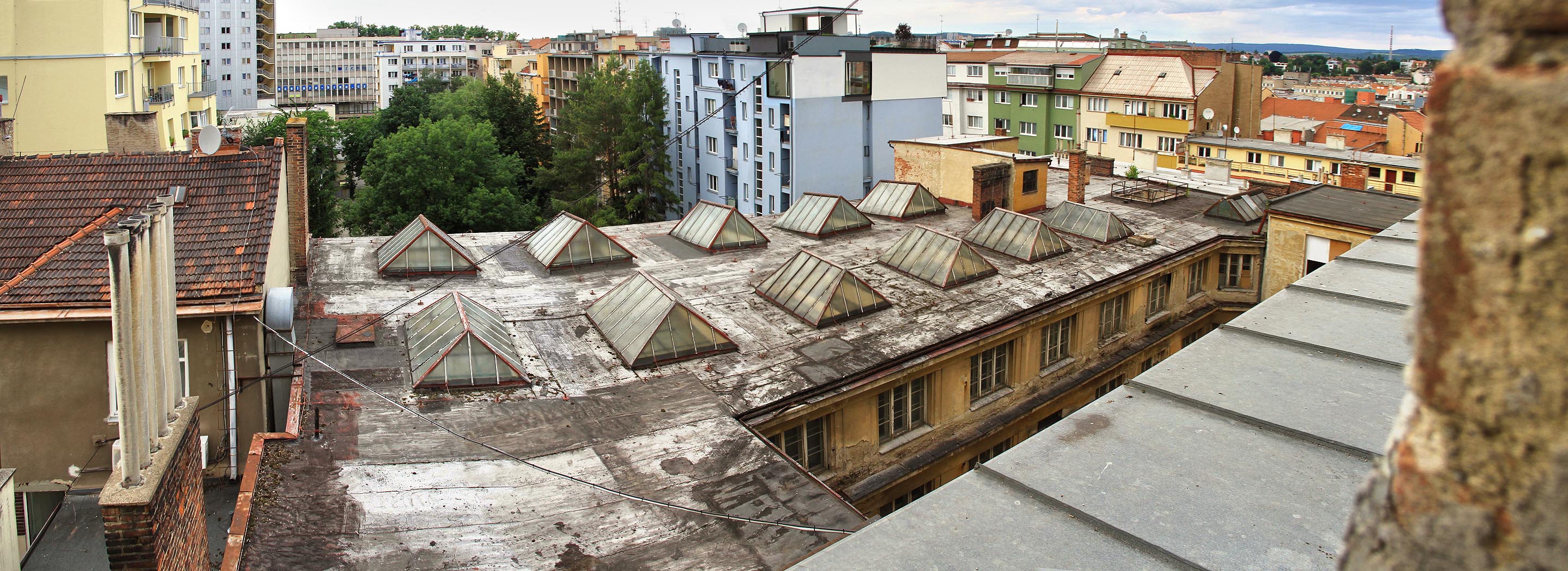 Z nejvyššího patra hlavní budovy je impozantní výhled do dvorních traktů Mášovy ulice, na hotel Continental (schodiště vlevo nahoře) a dokonce i na komín maloměřické cementárny.
