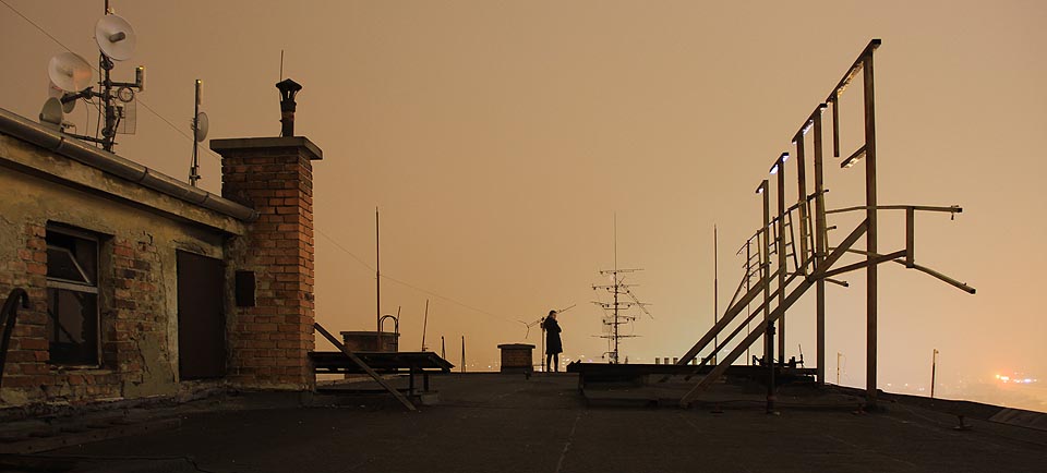 Když budete mít štěstí, potkáte možná na střeše plachou dívku, která zadumaně kouká na držák bývalého neonového nápisu. Jaká písmena jen mohly ty podivné tvary držet? Snad nějaké neznámé písmo ze zákoutí druhého Brna?