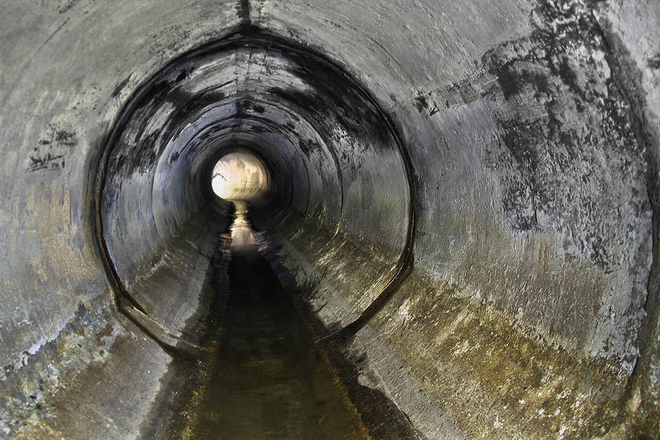 Mírný proud a veskrze čisté betonové stěny zatím nevěští nic zlého. Světlo v dálce pochází z baterek kolegů, kteří se soukají za námi.