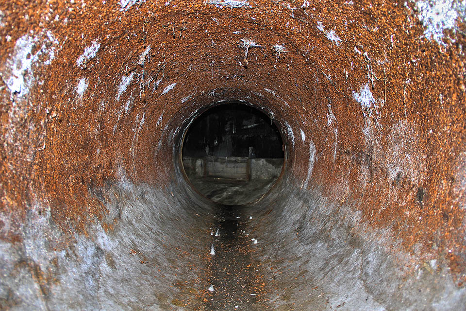 Kdo chce vidět víc, musí prolézt ocelovou rourou, ze které se drolí šupiny oranžové rzi. Splašková voda je chemicky agresivní a neustále zatížená potrubí se raději dláždí čedičem nebo vykládají laminátem.