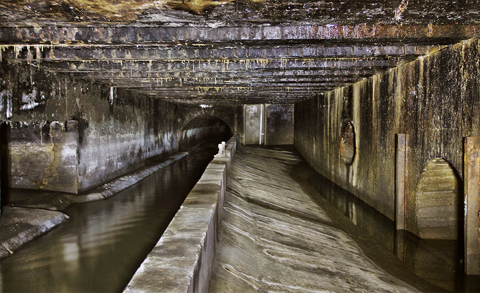 Přelivná hrana v odlehčovací komoře v celé své kráse. Za normálního stavu je hladina splaškové vody hluboko pod vrcholem hrany, v případě nadkritického množství vody v potrubí ji však přeteče a vchrstne bez čištění rovnou do řeky.