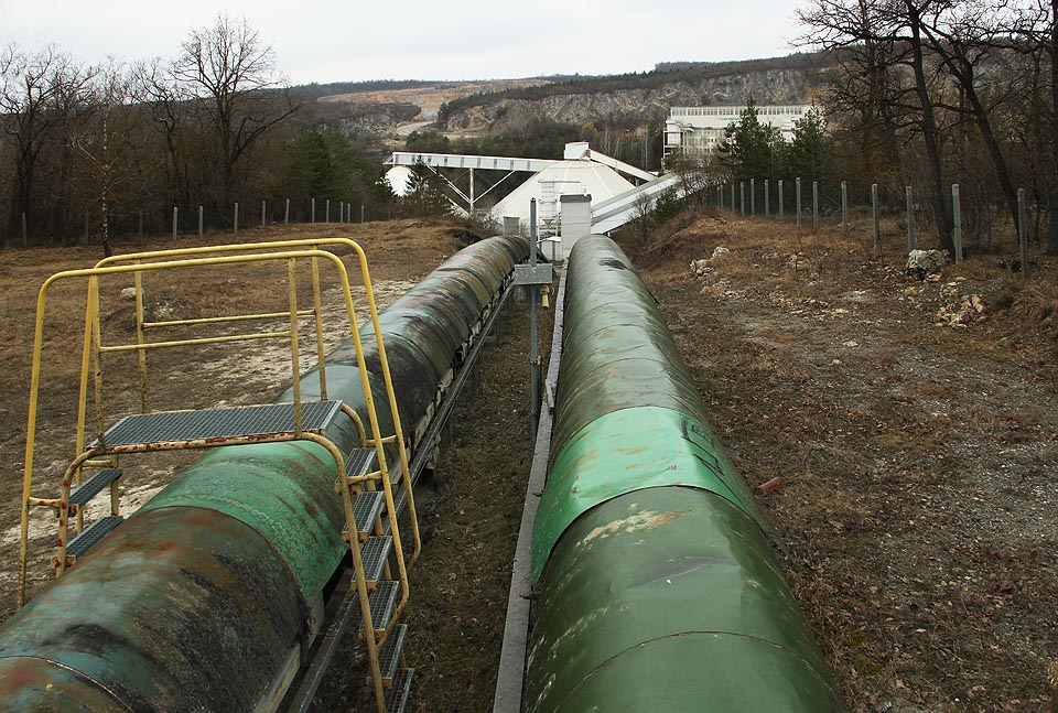 Začátek dvojice dopravníkových pásů je u krytého (dříve však volného) kuželového zásobníku suroviny na okraji lomu v Mokré. To, co vypadá jako pomačkané roury, jsou plechové kryty horního pásu. Začátek dvojice dopravníkových pásů je u krytého (dříve však volného) kuželového zásobníku suroviny na okraji lomu v Mokré. To, co vypadá jako pomačkané roury, jsou plechové kryty horního pásu.