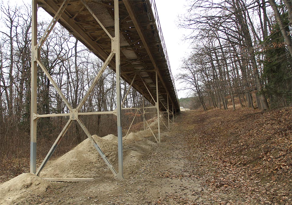 V posledním úseku se dopravník ještě jednou zvedá na mostní konstrukci nad cestu vedoucí kolem cementárny. Dál už se cesty kameniva větví do mnoha směrů. V posledním úseku se dopravník ještě jednou zvedá na mostní konstrukci nad cestu vedoucí kolem cementárny. Dál už se cesty kameniva větví do mnoha směrů.