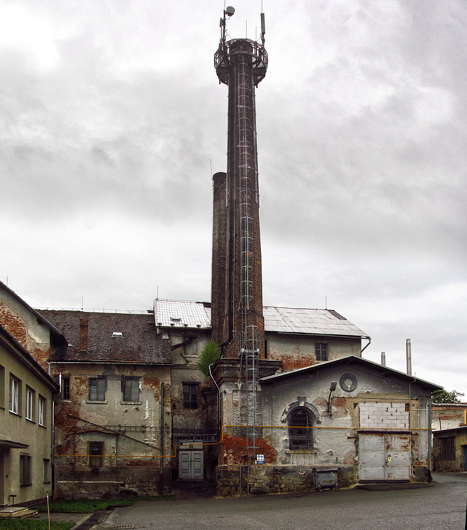 Dvojice komínů obrůstá zelení, zatímco zdivo budov sbírá vzpomínky na třetí století své existence.