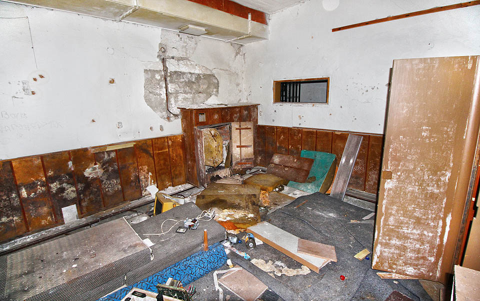 Vstoupit do budovy lze jedním z nouzových východů - např. tento je v menším sále umně ukryt v dřevěném obložení stěn.