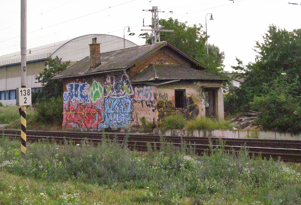 Drážní domek č. 53 a hektometrovník označující km 138,2 poblíž jižního zhlaví stanice Brno jih v létě roku 2014.