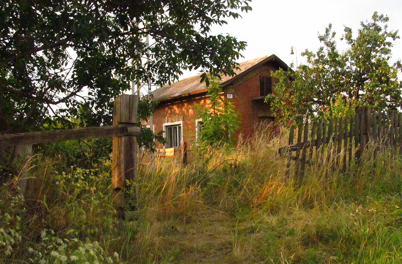 Při pohledu od jihozápadu se v roce 2014 strážní domek jevil jako oáza klidu a míru. Fotografie však klame: jen stěží si lze představit klidný život v těsné blízkosti železničního koridoru, po kterém burácí vlak každých pár minut, skřípání posunu z nádraží Brno jih, neustávajícího vyzvánění závor a hukotu z továrny, která se nachází jen pár desítek metrů od západní stěny domku. Tohle kdysi klidné místo bylo už před léty odsouzeno k věčnému šumu a huku.