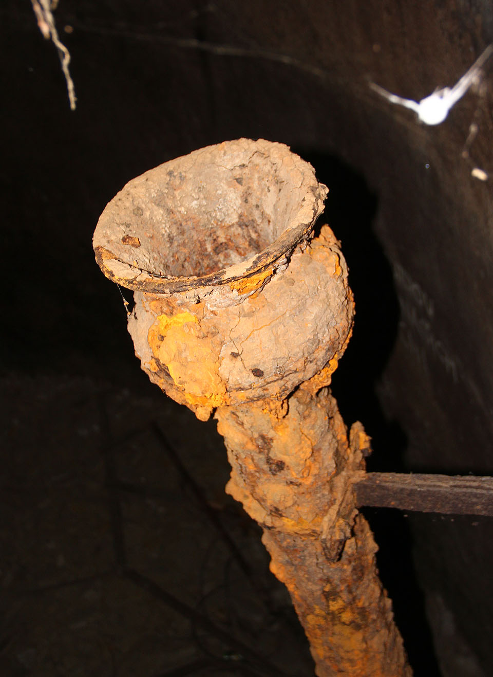 Voda je už desítky let pryč, přesto zůstává technické vybavení vodojemu ozdobenou růžicemi oranžové rzi. Horní výpusť u žebříku do hlavní nádrže.