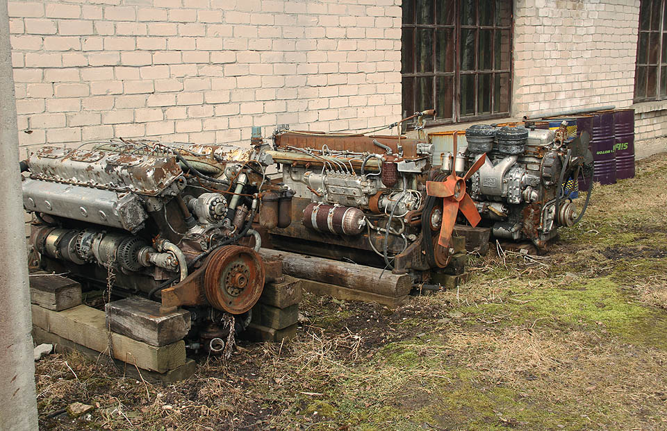 Za výtopnou se u zdi povaluje hned několik motorů ze sovětských úzkokolejných lokomotiv.