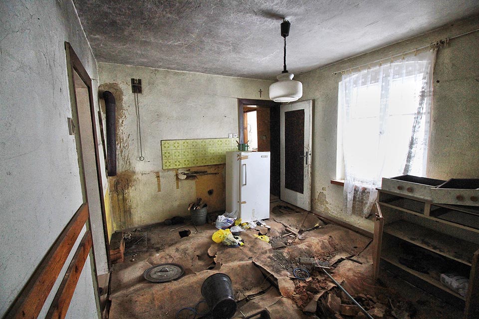 V kuchyni chybí sporák a podlaha se v nevytápěném, vlhkém domě změnila v rozeklané pohoří. V kuchyni chybí sporák a podlaha se v nevytápěném, vlhkém domě změnila v rozeklané pohoří.