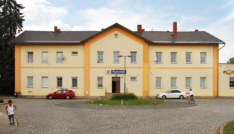 Pohled na nádražní budovu ze směru podél bezejmenné ulice od kulturního domu. Pohled na nádražní budovu ze směru podél bezejmenné ulice od kulturního domu.