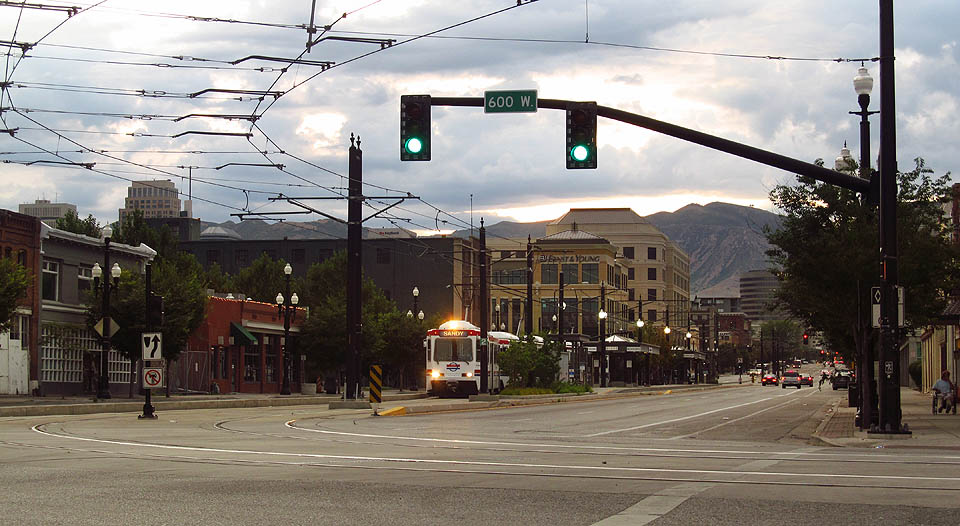 Ranní vlakotramvaj systému TRAX ve směru Sandy přijíždí po ulici 200 South a chystá se zabočit k nádraží na ulici 600 West.