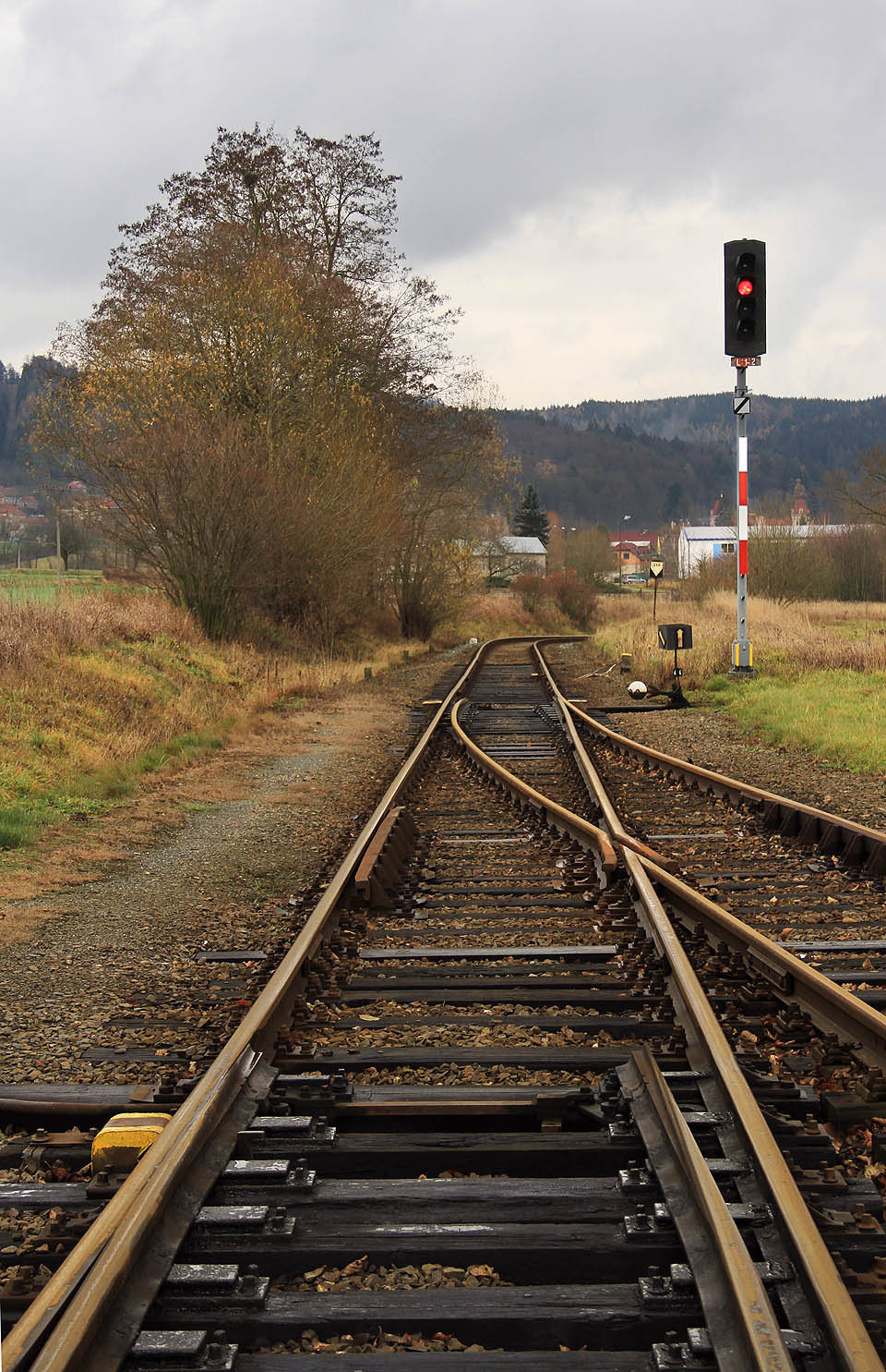 Pohled na jížní zhlaví stanice Šebetov. Nádraží se nachází na kopci a uprostřed esovitého dvojoblouku, pročež se ze stanice vždy vyjíždí směrem doprava. V dálce je vidět hala dřevařských závodů na místě, kde odbočuje z koleje vlečka.