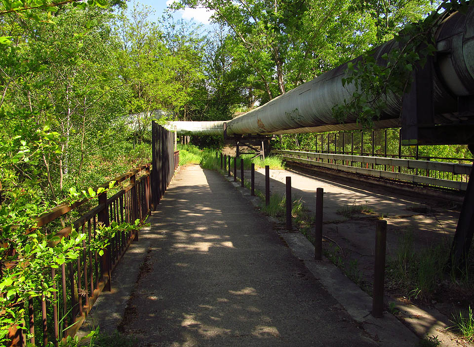 Zelený had potrubí se vine přes most nad kolejemi do depa a dále kilometry po úbočí Hád až k sídlištím, kvůli kterým byl kdysi vybudován.