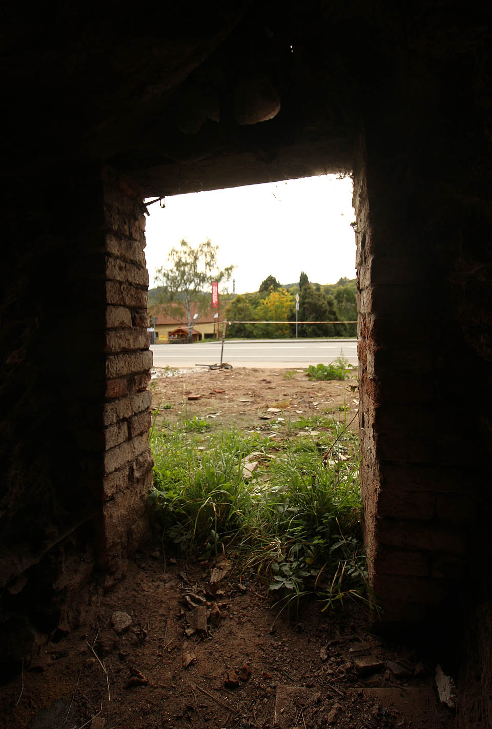 Trochu syrový pohled ven na silnici č. I/43 a místo, kde stál pod skálou přes sto let typický domeček s břidlicovou střechou.