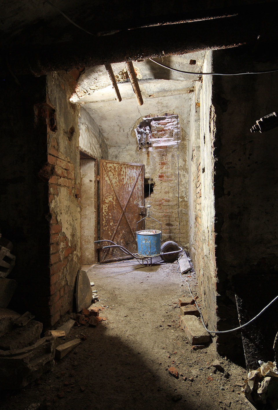 Ani třičtvrtěstoletí chátrání pod zemí bez přístupu vzduchu a světla nezničilo ocelové dveře sklepa. V modré plechovce dělníci vyváželi suť v rámci sanace roku 2022.