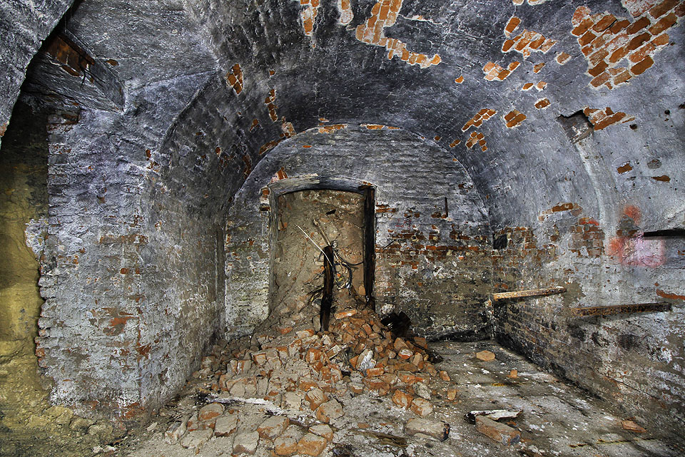 Také na východní straně pokračuje podzemí do další místnosti - jediné nevydřevené, za to se dvojicí dveří vedoucích doslova do nitra země. Dovnitř se valí hlína a suť, kterou kdysi někdo podzemí zavalil.