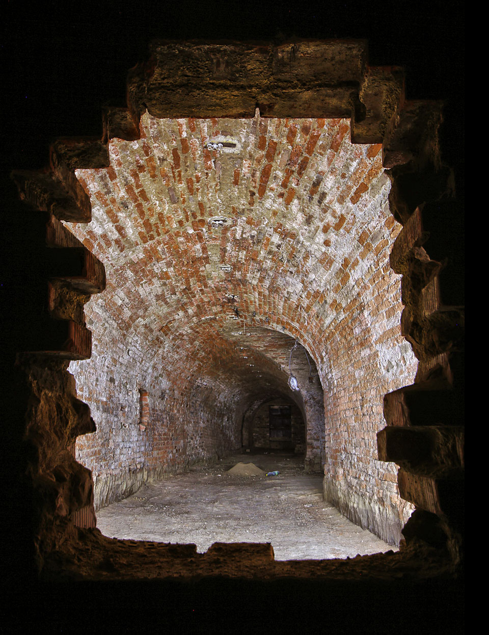 Pohled skrze příčku, která rozdělila sklepy za domem č. na přední a zadní část. Osvětlený prostor je tvořen písmenem T do směrem ulice, tmavá zadní část byla dodatečně připojena ke sklepům domu Hlinky 62.