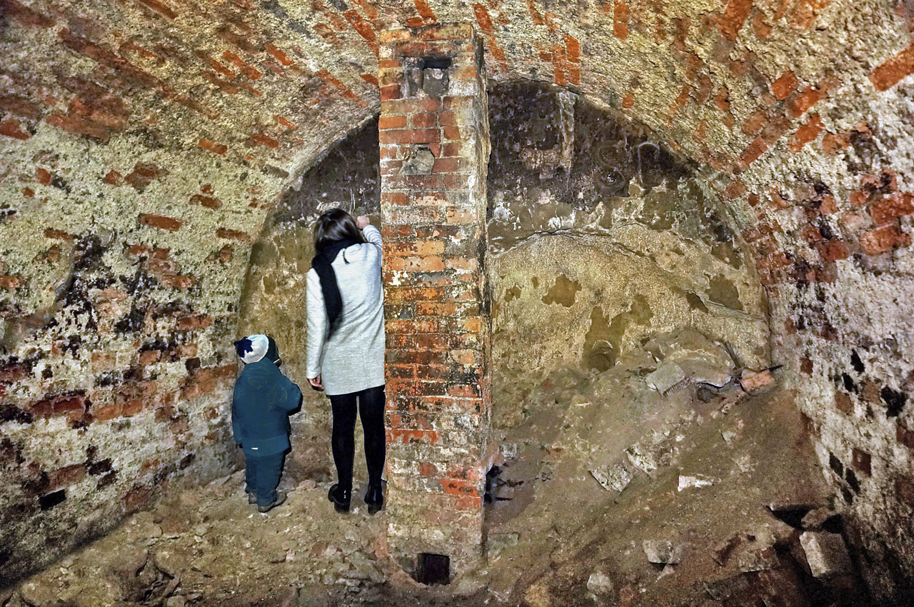 V místnosti zaujme komín, který zřejmě umožňoval vytápět část podzemních prostor, a záhadná čtveřice písmen vyrytá do poměrně tvrdé sprašové horniny tvořící zadní stěnu chodby.