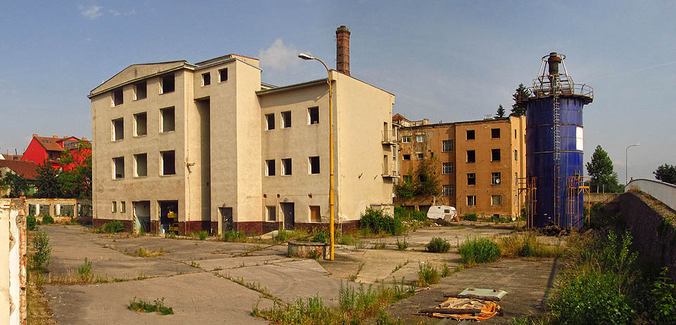 Pohled na západní polovinu areálu přeťatého prodloužením Střední ulice (na rampě vpravo) v roce 2014. Poslední stroje se dotočily před 11 roky, areál ale stále hlídá ostraha s krvelačným psem.