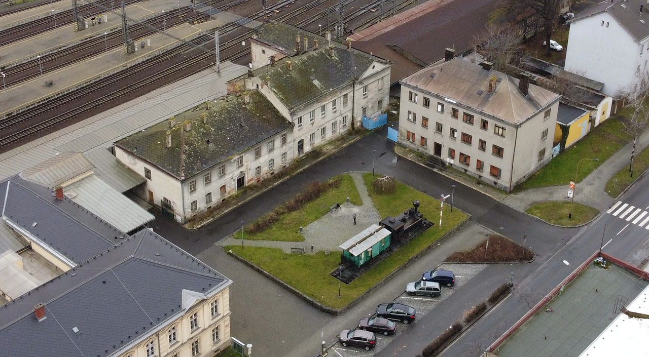Před původní výpravní budovou se rozkládá malé náměstíčko s lokomotivním pomníkem (tzv. Kafemlejnkem), sevřené mezi novou výpravní budovu, původní stanici a modernější budovu pošty, v roce 2023 rovněž opuštěnou.